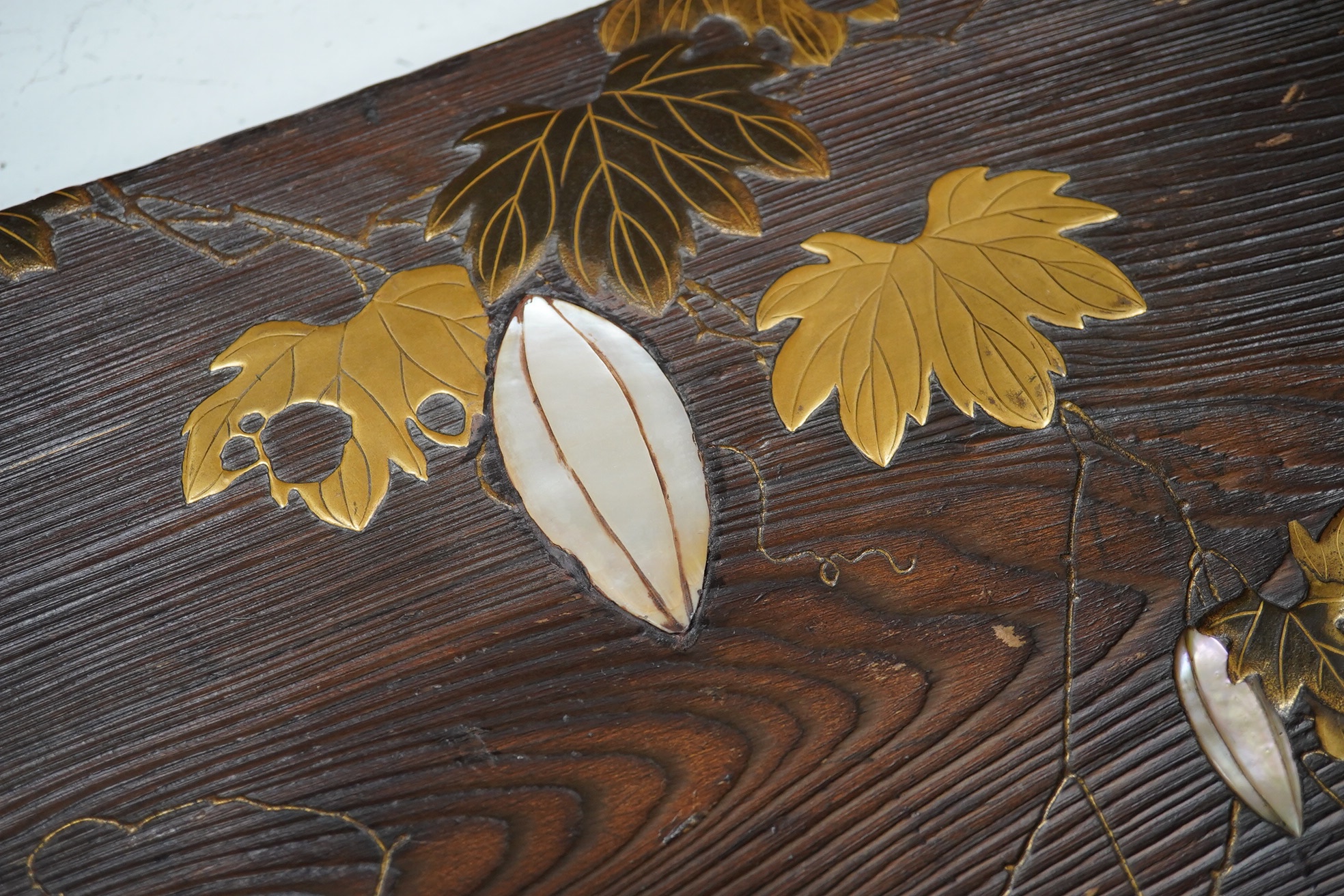 A 19th century Japanese grained wood and lacquer work panel, with mother-of-pearl flower buds, 29 x 55cm. Condition fair to good, minor chips and scratches to the wood.